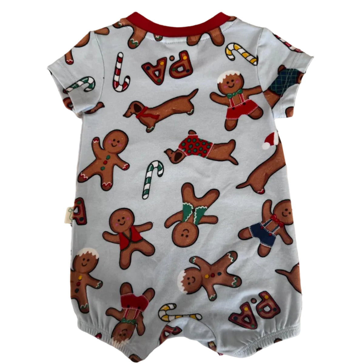 A baby short-sleeve romper in light gray with a festive Christmas print featuring gingerbread men, dachshunds, candy canes, and red 'PA' lettering, laid flat on a speckled beige countertop.