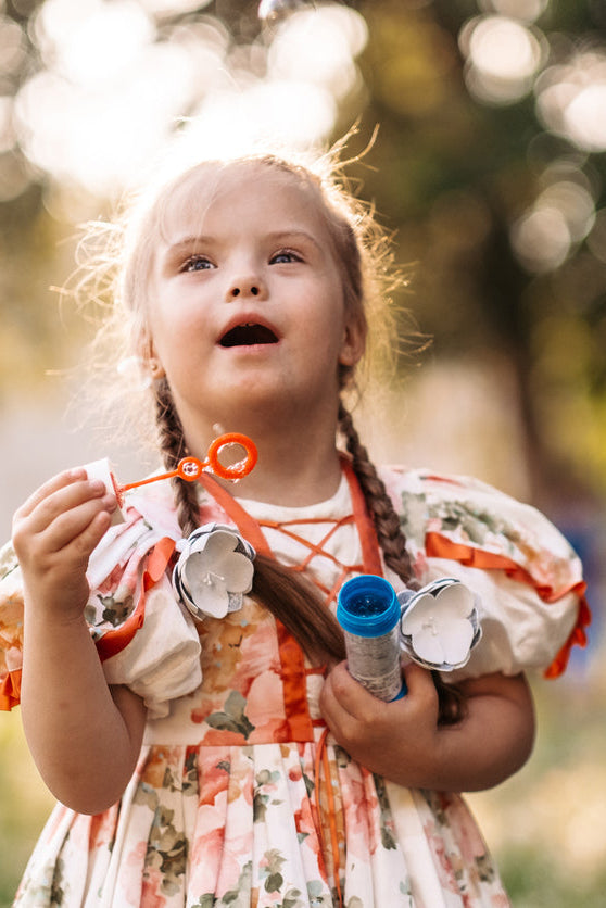 Young girl blowing bubbles outdoors with a blurred natural background